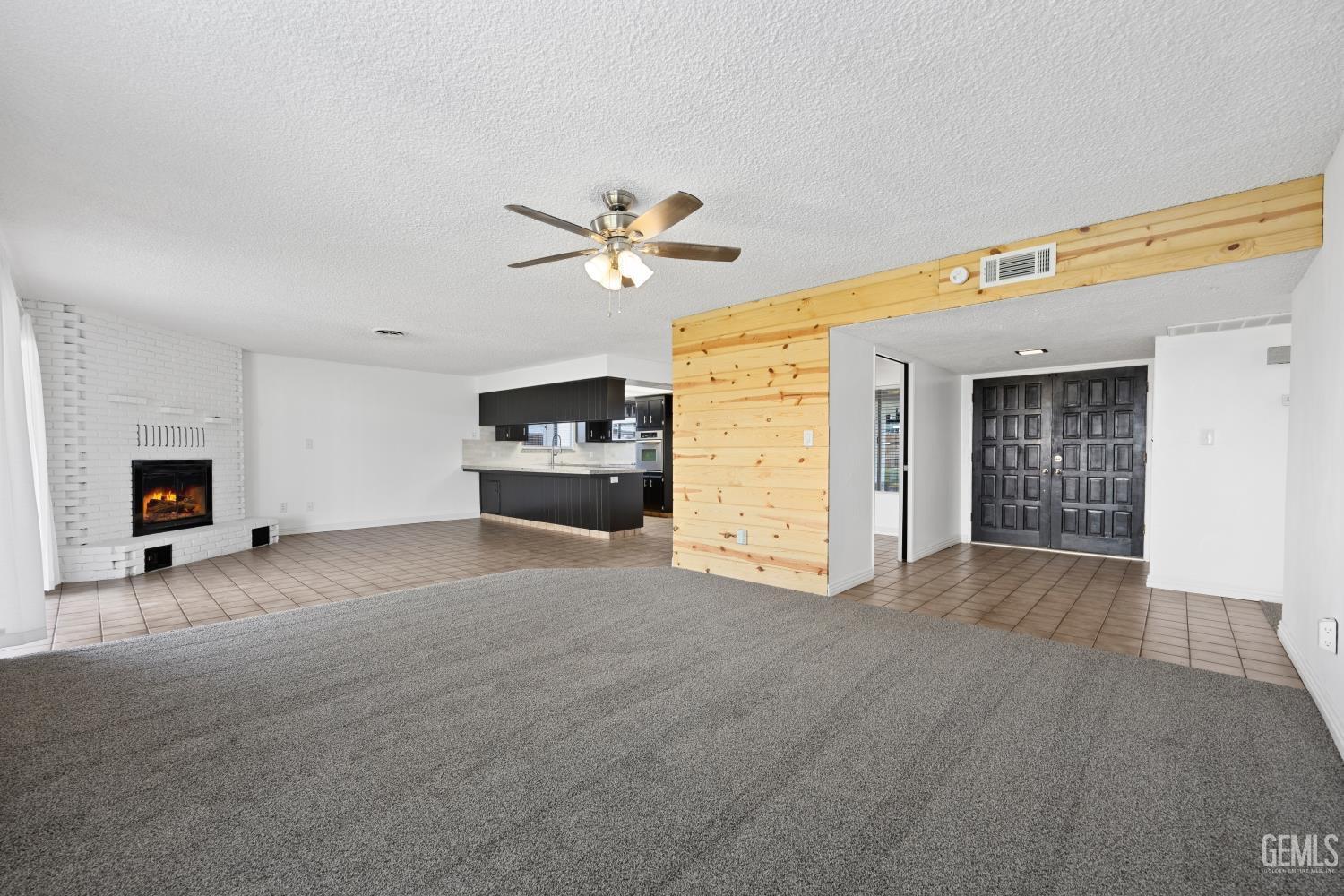 Undisclosed Address Bakersfield, CA 93312 - Photo 7 of 30 a view of a livingroom with a fireplace a ceiling fan and wooden floor