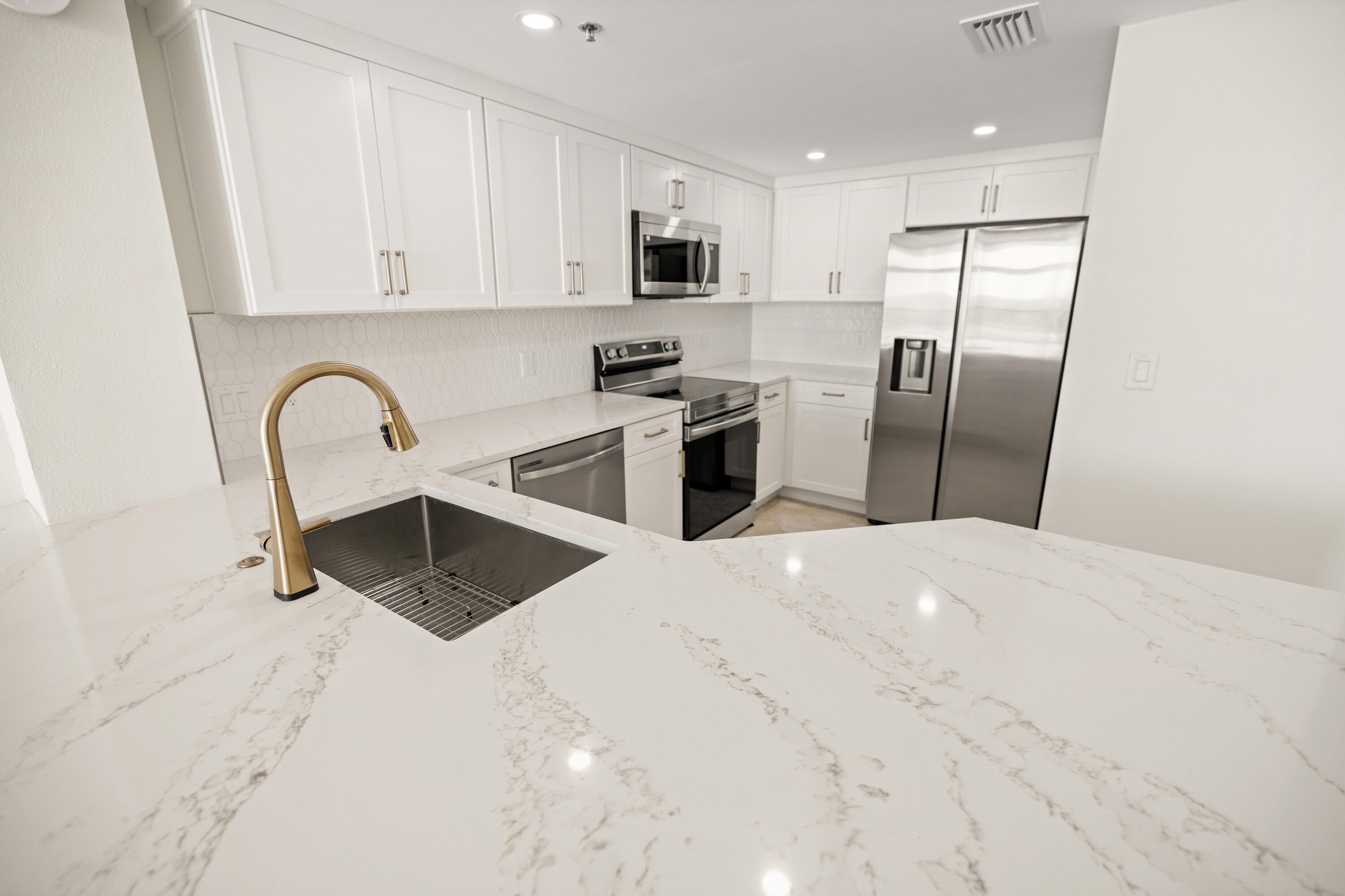 1018 Highway 98, Unit 340 Destin, FL 32541 - Photo 17 of 62 a kitchen with stainless steel appliances granite countertop a refrigerator a stove a sink a microwave and white cabinets with wooden floor