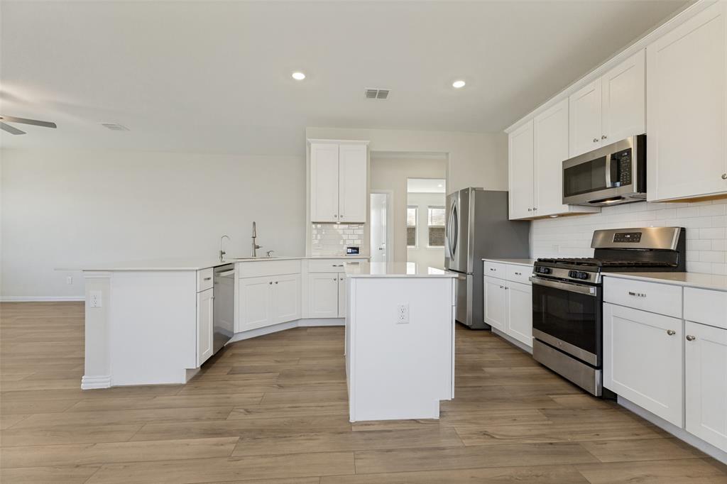 1237 Almond Road Azle, TX 76020 - Photo 5 of 24 a kitchen with cabinets stainless steel appliances and wooden floor