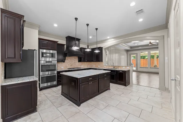 a kitchen with stainless steel appliances granite countertop a sink a stove and a wooden cabinets