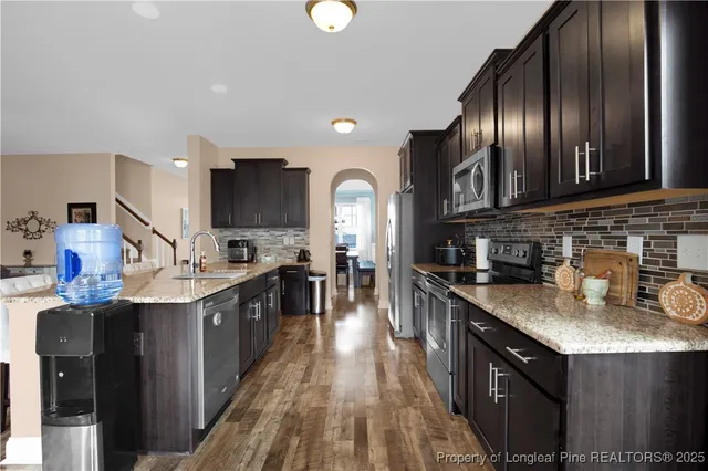 a kitchen with stainless steel appliances granite countertop a sink a stove and a wooden floors