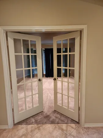 an empty room with a chandelier fan and windows