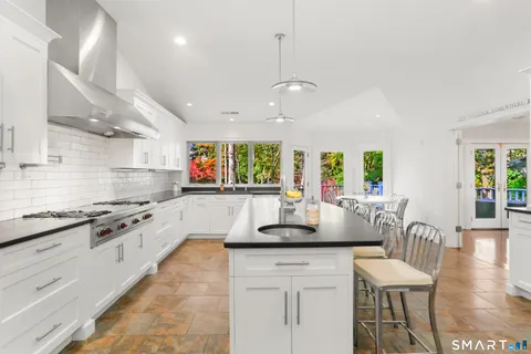 a kitchen with stainless steel appliances granite countertop a stove a sink a dining table and chairs with wooden floor