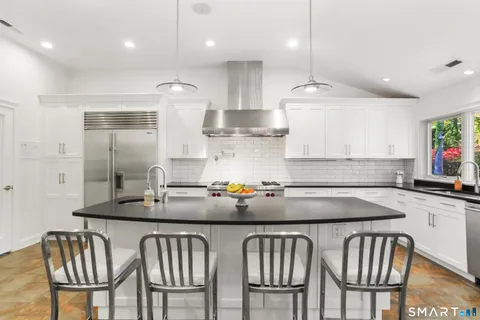 a kitchen with stainless steel appliances granite countertop a table chairs sink and cabinets