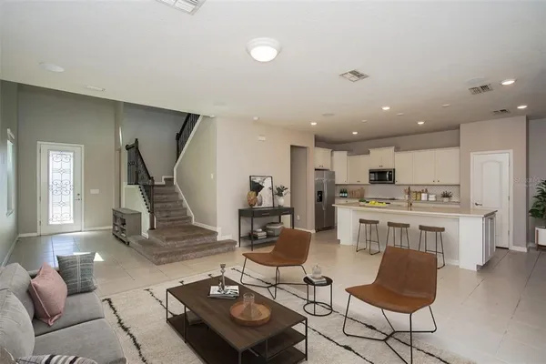 a living room with furniture kitchen view and a wooden floor