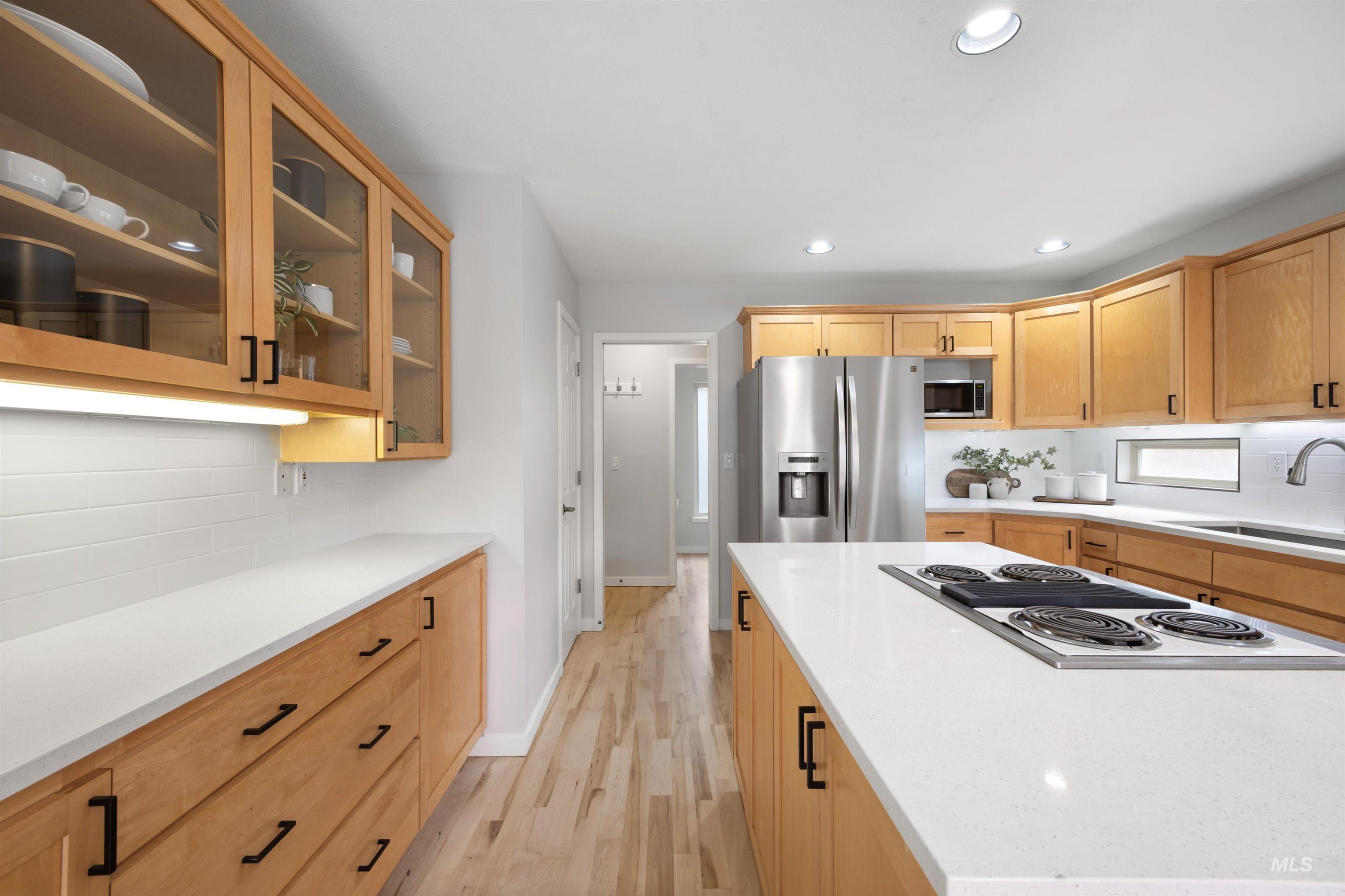 1313 Martin Street Boise, ID 83706 - Photo 26 of 46 Kitchen with glass fronted cabinets, stainless steel appliances, light wood-style flooring, tasteful backsplash, and light wood finish cabinets