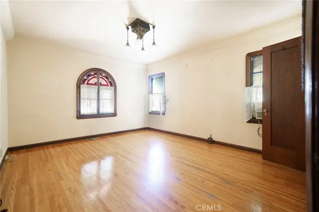 a view of an empty room with a window and wooden floor
