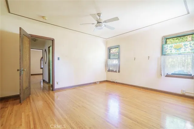 an empty room with wooden floor fan and windows