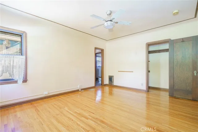 a view of an empty room with wooden floor and a window