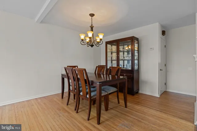 a dining room with wooden floor a chandelier a wooden table and chairs