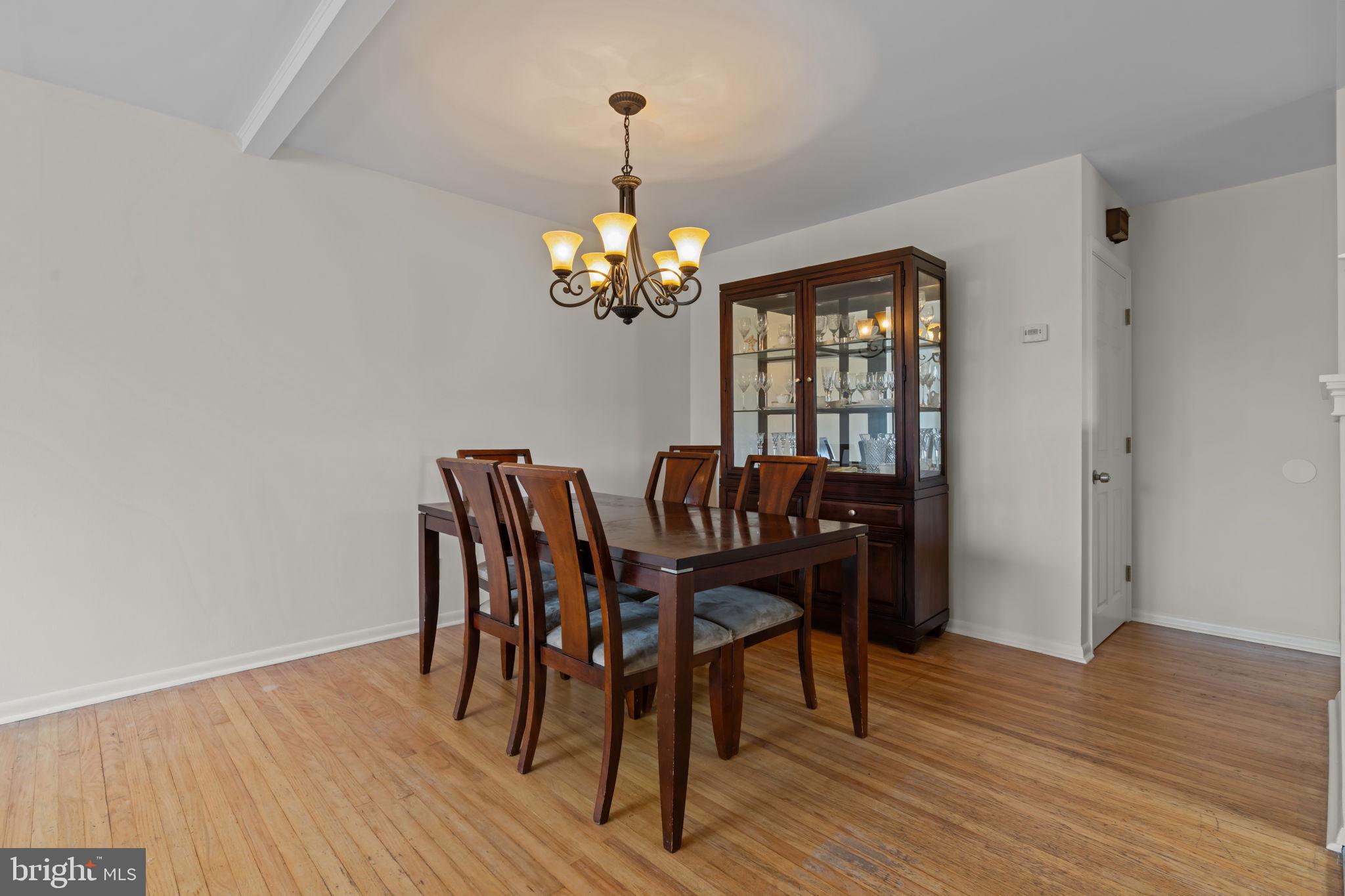 13039 Stevens Road Philadelphia, PA 19116 - Photo 6 of 32 a dining room with wooden floor a chandelier a wooden table and chairs
