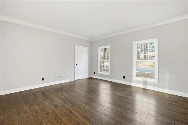 an empty room with wooden floor and window