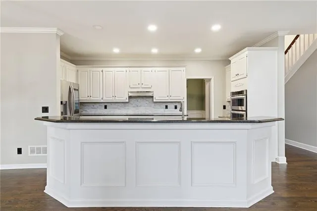 a kitchen with stainless steel appliances granite countertop a sink a stove and a refrigerator