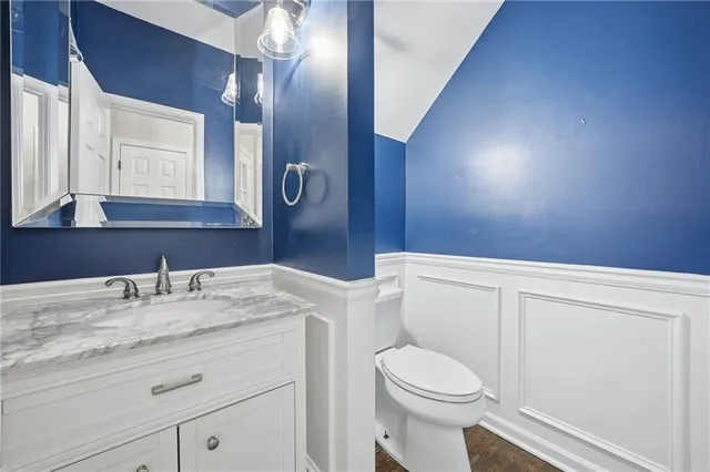 a bathroom with a granite countertop sink mirror vanity and toilet