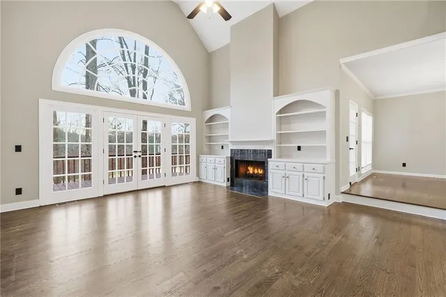 an empty room with wooden floor a fireplace and windows