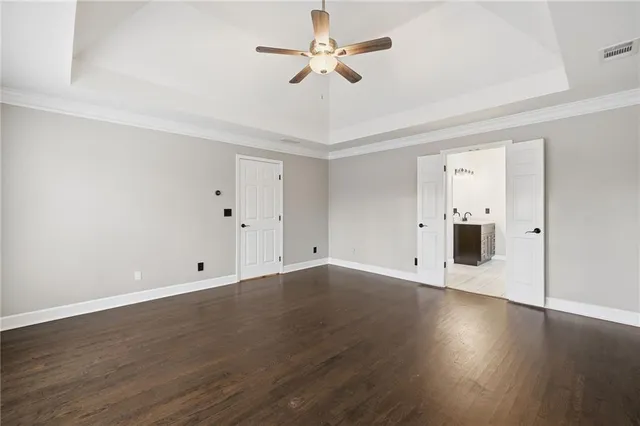 an empty room with wooden floor and ceiling fan