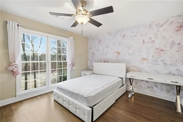a bedroom with a bed and a large window with wooden floor