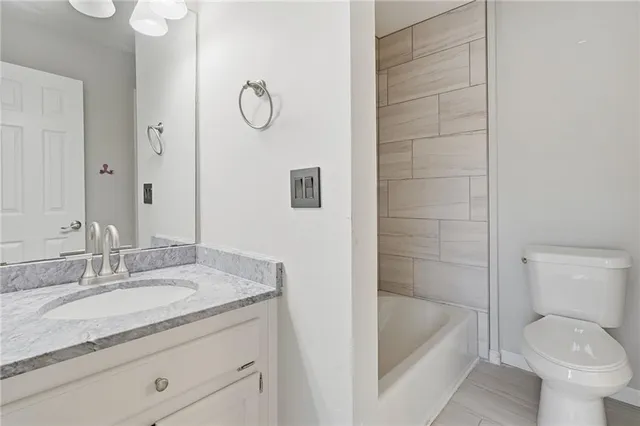 a bathroom with a granite countertop sink a toilet and bathtub