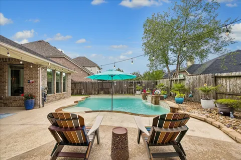 a view of a patio with a dining table and chairs under an umbrella with a fire pit and a fire pit