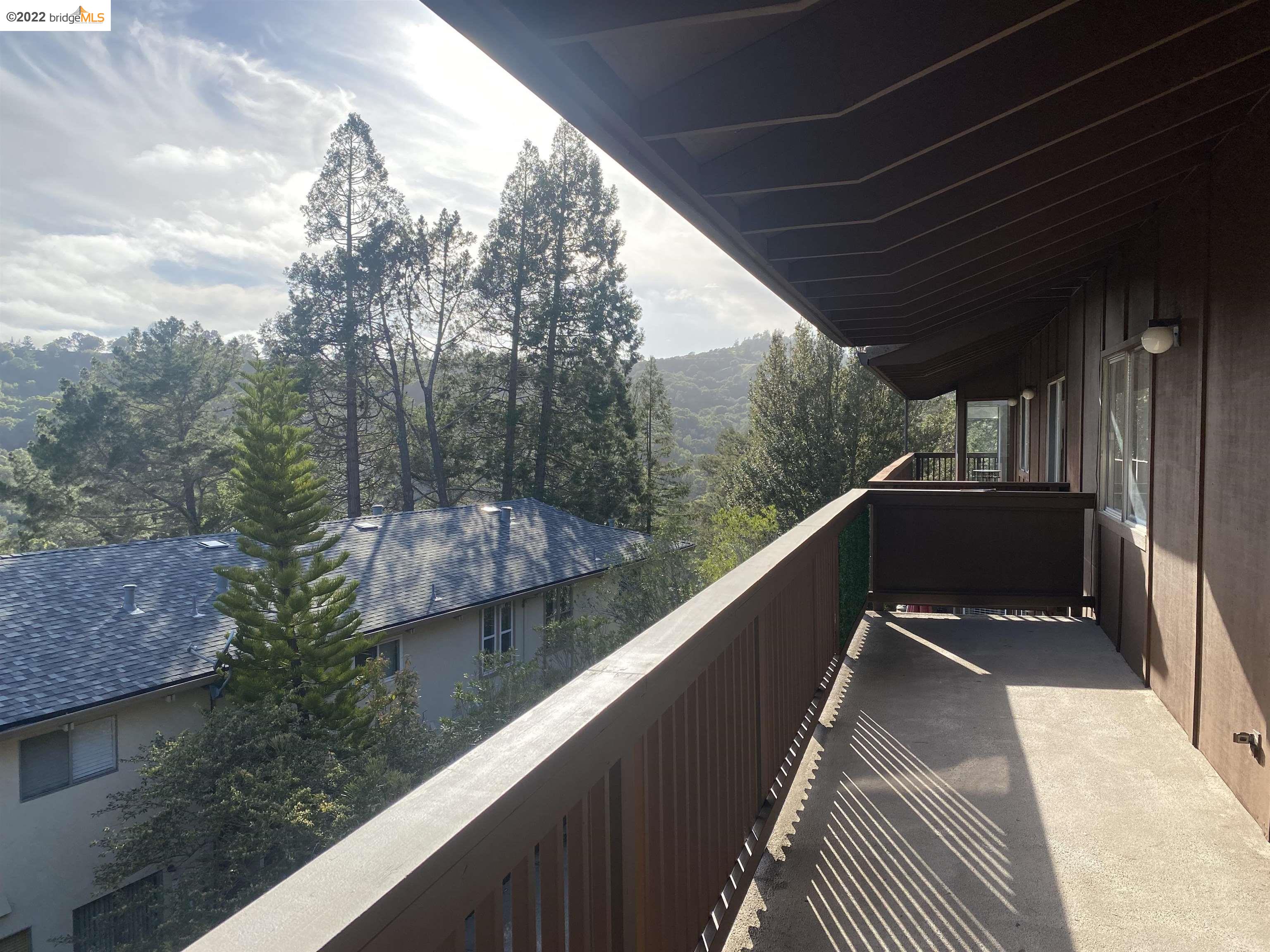 a balcony view with two plants and a barbeque