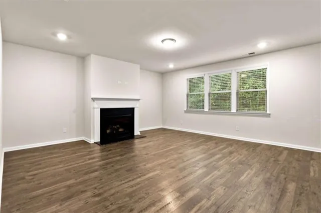 an empty room with wooden floor fireplace and windows
