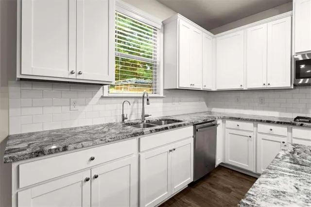a kitchen with granite countertop white cabinets and a sink