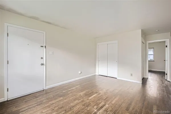 a view of an empty room with wooden floor and closet
