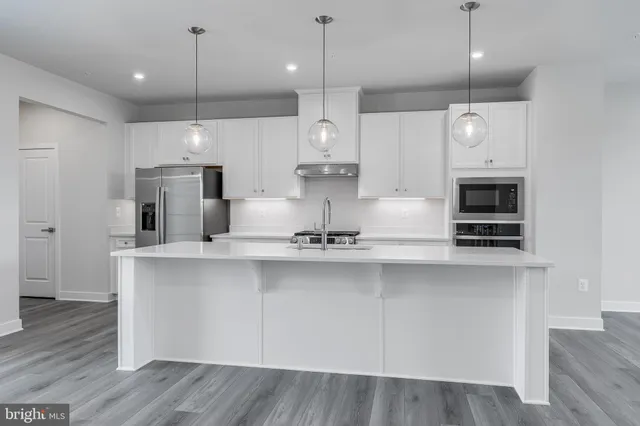 a large white kitchen with lots of counter space a sink appliances and cabinets