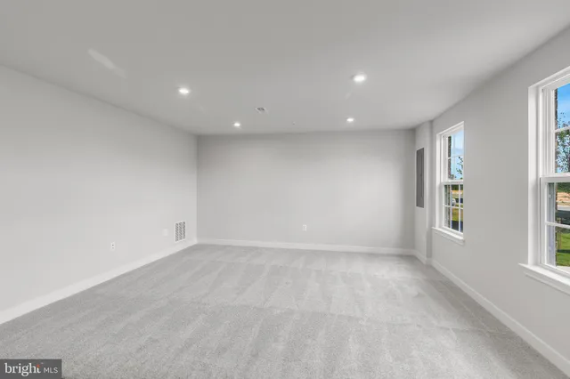 a view of an empty room with wooden floor and a kitchen