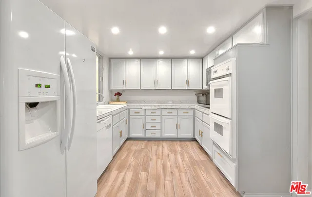 a kitchen with white cabinets and a window