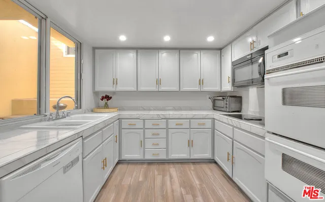 a kitchen with granite countertop white cabinets and stainless steel appliances