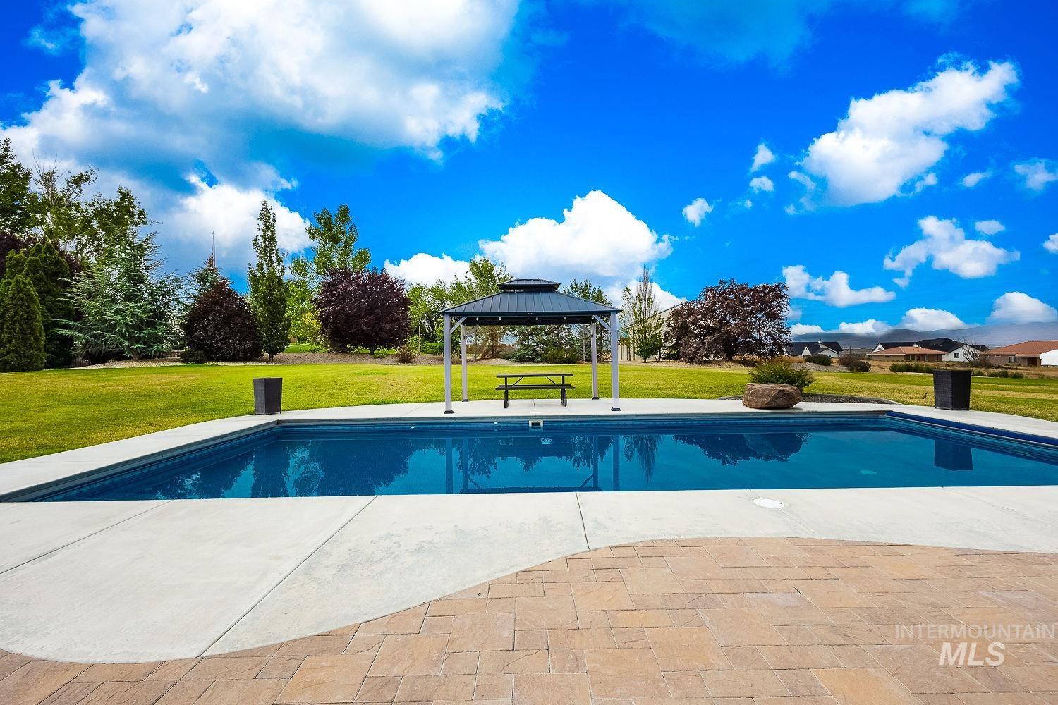 8077 Star Pass Ridge Road Nampa, ID 83686 - Photo 7 of 37 Expansive backyard featuring a rectangular swimming pool, concrete pool decking, and an adjacent paver patio