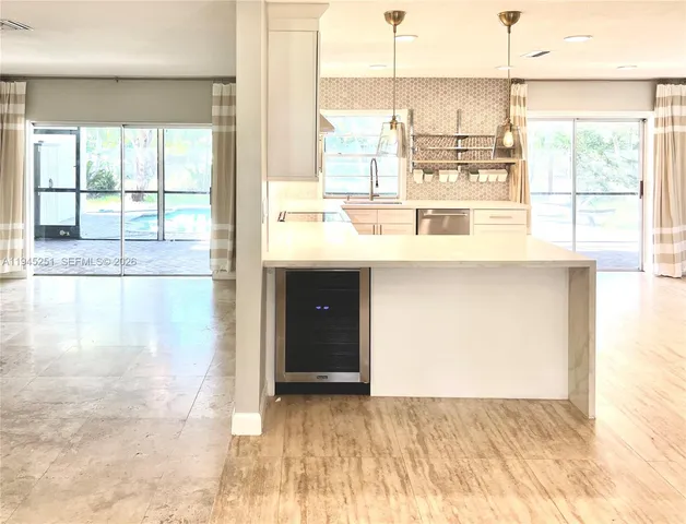 a view of a kitchen with kitchen island a sink windows and a dining table