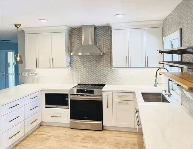 a kitchen with stainless steel appliances granite countertop a stove and a white cabinets