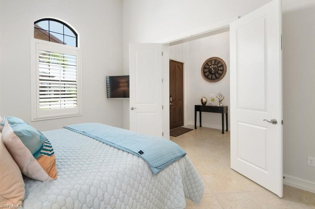 7606 Trento Circle Naples, FL 34113 - Photo 19 of 28 a bedroom with a bed and a lamp next to a window