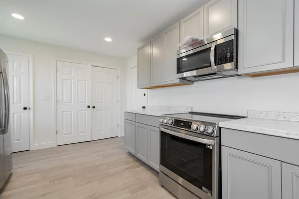 a kitchen with stainless steel appliances granite countertop a stove a microwave and white cabinets