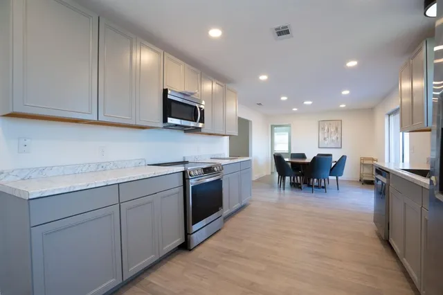 a kitchen with kitchen island granite countertop stainless steel appliances stove sink microwave and cabinets