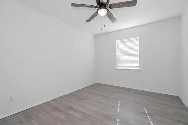 an empty room with a window and a fan