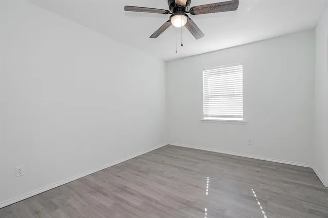 an empty room with a window and a fan