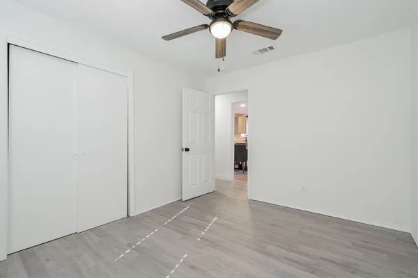 wooden floor in an empty room with a chandelier fan