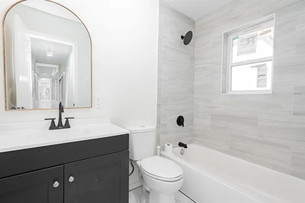 a bathroom with a bathtub shower sink vanity mirror and toilet