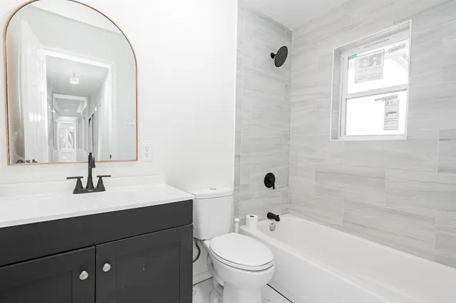 a bathroom with a bathtub shower sink vanity mirror and toilet