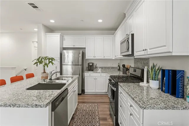 a kitchen with kitchen island granite countertop a sink stainless steel appliances and white cabinets