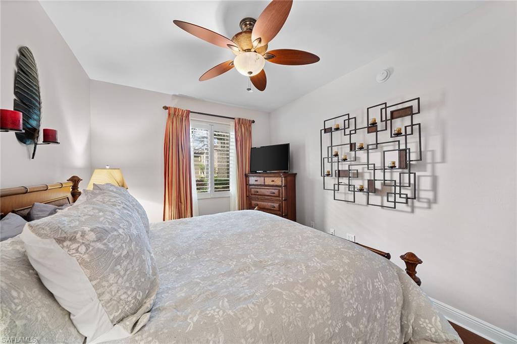 1015 Sandpiper Street, Unit D105 Naples, FL 34102 - Photo 19 of 39 a bedroom with a large bed a flat tv screen and a dresser