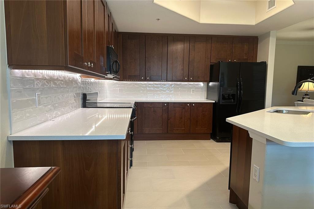 1015 Sandpiper Street, Unit D105 Naples, FL 34102 - Photo 8 of 39 a kitchen with a sink a refrigerator and cabinets