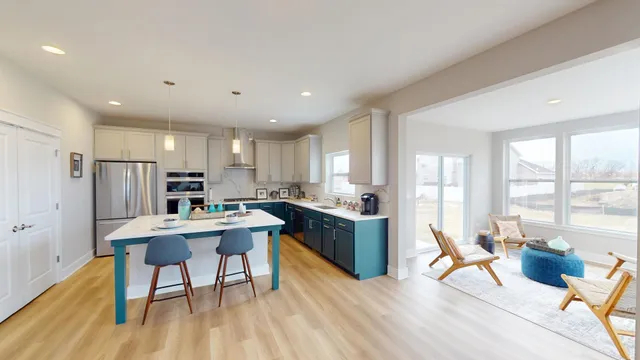 a kitchen with stainless steel appliances kitchen island granite countertop a refrigerator a stove a sink dishwasher with a dining table and chairs with wooden floor