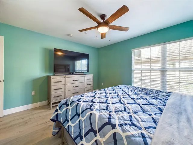 a bed sitting in a bedroom next to a window and a flat screen tv