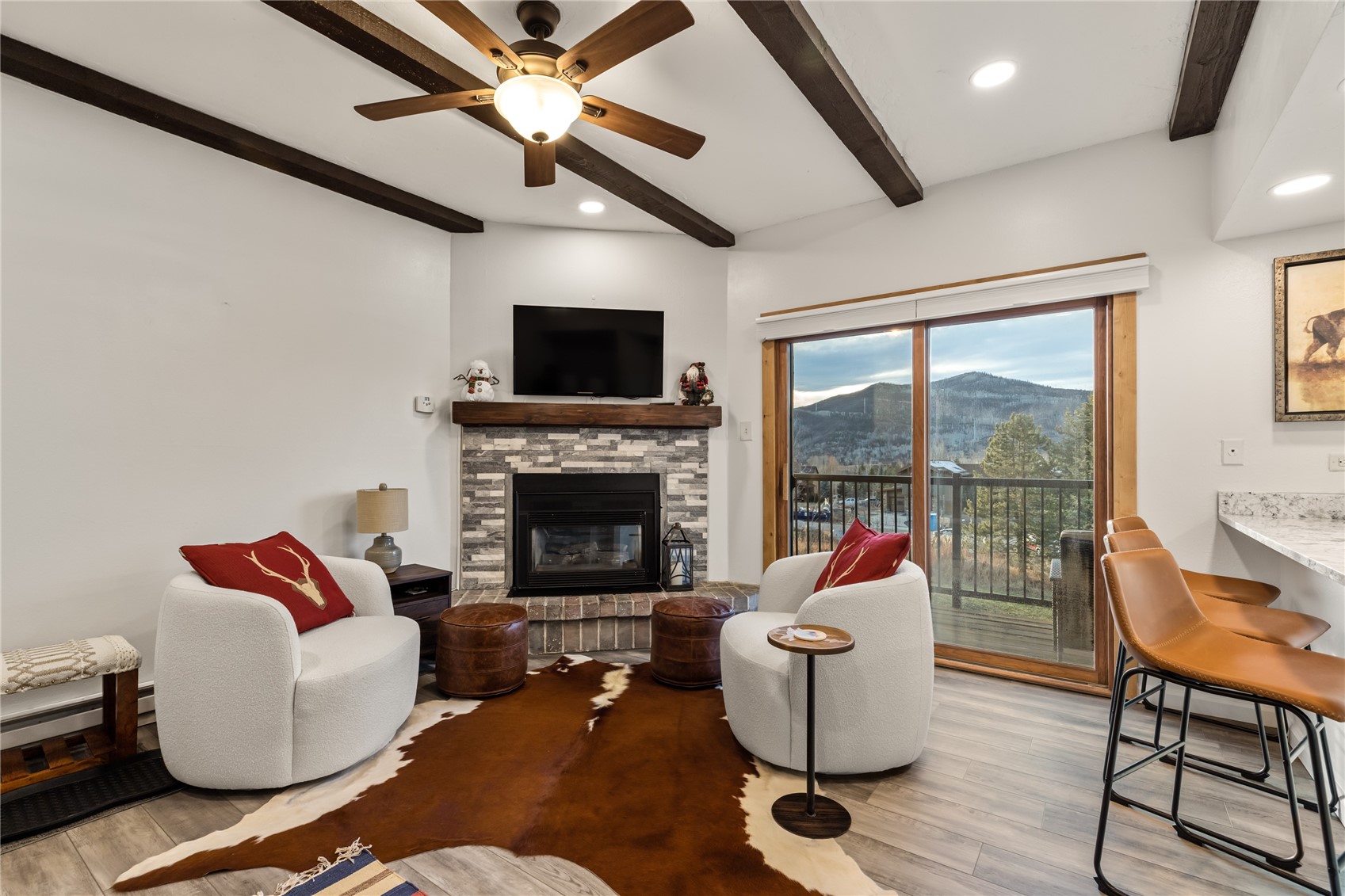 1945 Cornice Road, Unit 2224 Steamboat Springs, CO 80487 - Photo 6 of 22 Living room with light wood-type flooring, a stone fireplace, beam ceiling, and ceiling fan
