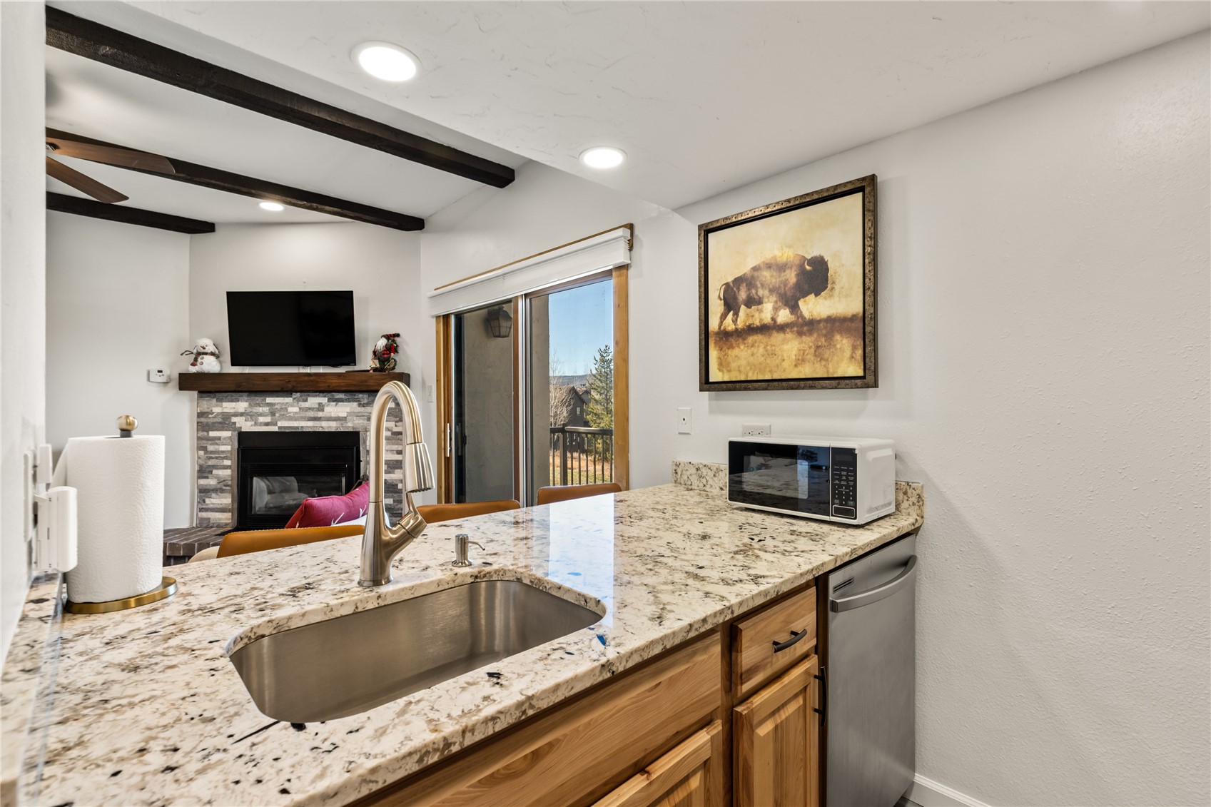 1945 Cornice Road, Unit 2224 Steamboat Springs, CO 80487 - Photo 8 of 22 Kitchen with a stone fireplace, light stone countertops, beamed ceiling, ceiling fan, and sink