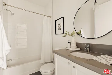 a bathroom with a granite countertop sink a toilet and a mirror